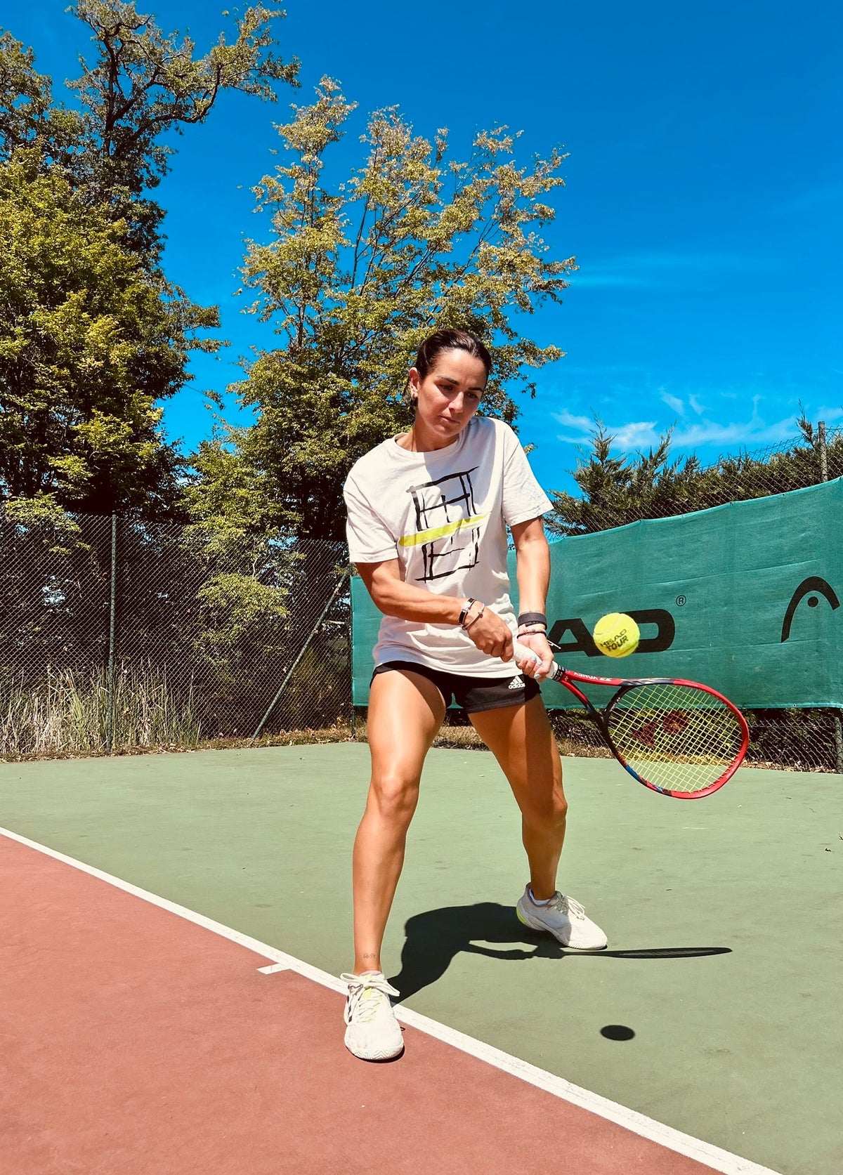 Joueuse de tennis en t-shirt /RAM frappant un revers en plein soleil