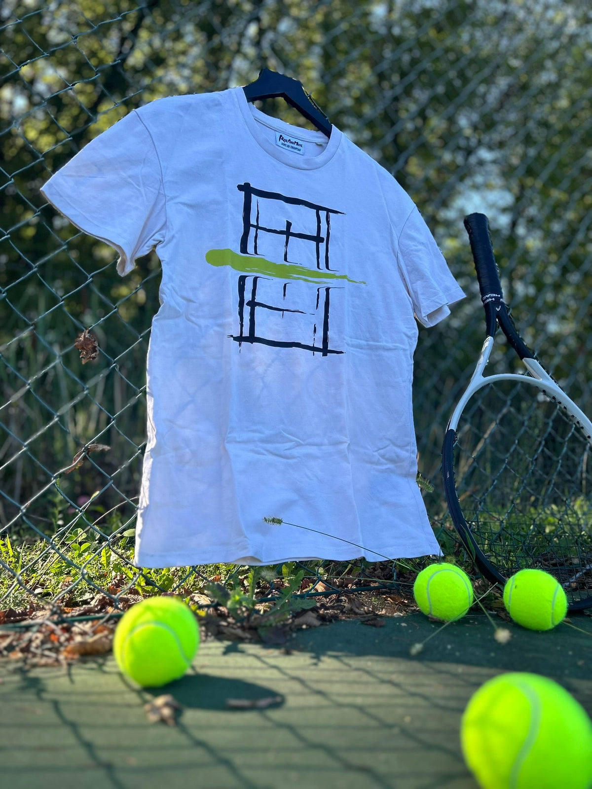T-shirt blanc /RAM à imprimé terrain, posé sur un grillage avec des balles